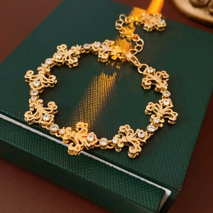 Gros plan d'un bracelet vintage Fleur-de-lis doré avec cristaux sur écrin vert luxe