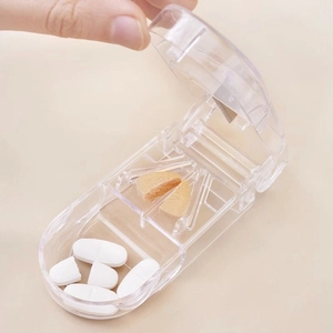Portable transparent pill cutter with metal blade showing hand cutting medicine tablet