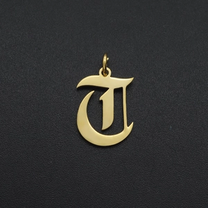 Macro shot of a gold gothic letter T pendant with a polished mirror finish on black
