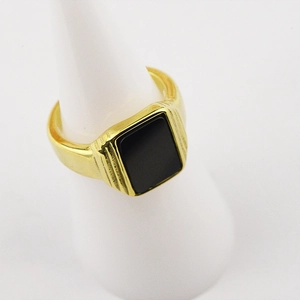 Vue macro d'une chevalière en acier plaqué or 18 carats avec pierre carrée noire