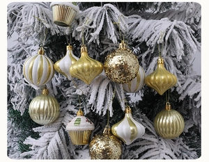 Detailed view of assorted gold and white Christmas ornaments on snow-covered pine branches