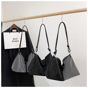 Three sparkly black rhinestone hobo bags hanging on a wood bar in an elegant setting