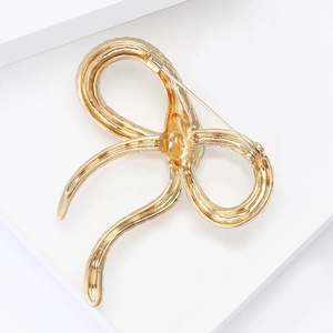 Detailed back view of golden bow brooch showing durable metal alloy pin structure