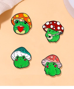 Detail view of four creative frog and mushroom enamel pins with vibrant colors