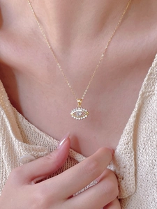 Close-up of a 925 silver golden evil eye pendant necklace worn on a woman's neck