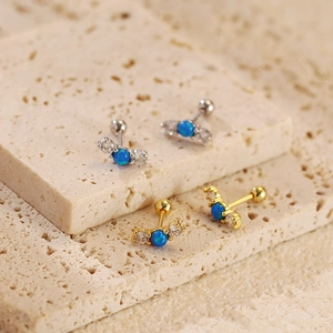 Detailed macro of opal cartilage studs with cubic zirconia on travertine stone