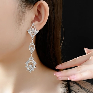 Macro side view of a model wearing sparkling teardrop hollow drop earrings for gala events