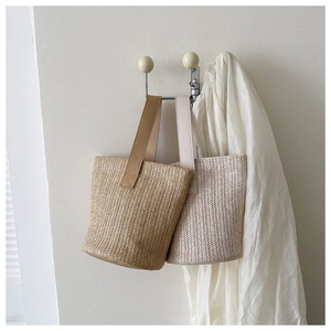 Detail of summer straw bucket bags with herringbone weave and leather handles
