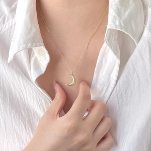 Detailed close-up of a golden crescent moon and star pendant on a dainty gold chain