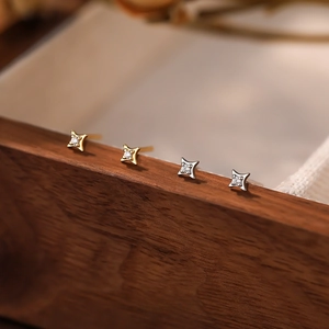 Macro shot of S999 silver four-point star earrings in gold and silver with zircon