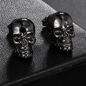 Close-up of hip-hop skull stud earrings in black metal on leather background