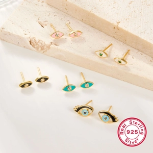 Detail view of colorful S925 sterling silver evil eye stud earrings on stone backdrop
