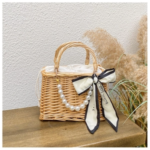 Detail of handmade woven straw bag with pearl chain, fabric liner and silk scarf