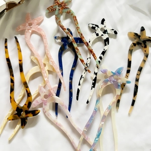 Starfish acetate U-shaped hair pins in various colors on white fabric background