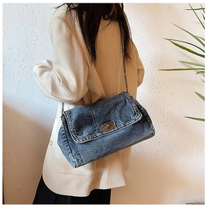 Detailed view of the dark blue denim chain shoulder bag worn by a model in a casual setting