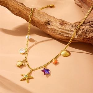 Gold necklace with turtle, starfish, shell, and pearl charms on rustic wood backdrop