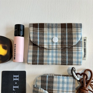 Detailed top view of a vintage plaid mini pouch with a snap button on a wooden surface