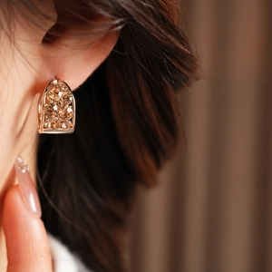 Gros plan de boucles d'oreilles vintage en forme de U dorées avec cristaux sur l'oreille