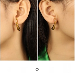 Detailed macro view of gold-plated teardrop earrings with green gemstone accents