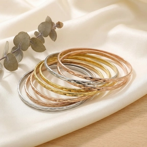 Macro shot of stainless steel bangles with diamond-cut patterns on silk fabric