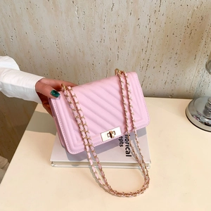 Pink quilted chain bag with gold metal clasp and elegant chevron pattern in hand