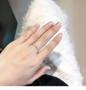 Close-up of a silver ring with an emerald-cut zircon on a finger, sparkling in detail
