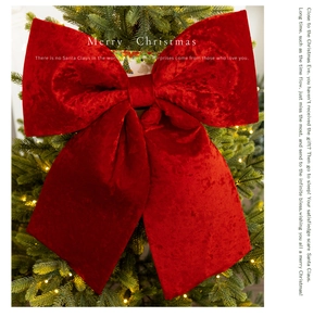 Detail of a large red velvet bow ornament with flowing ribbons on a Christmas tree
