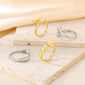 Dettaglio di anelli a goccia fluidi in oro e argento su pietra e seta elegante