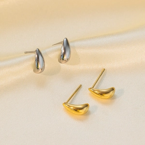 Minimalist stainless steel teardrop stud earrings in gold and silver on silk fabric