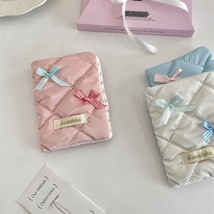 Detailed view of quilted bow passport holders in pink, white, and light blue colors