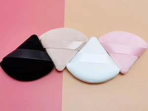 Flat lay of colorful triangular velvet makeup puffs with matching silk ribbons for setting