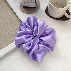 Macro detail of lavender satin scrunchie with soft silk texture and elegant pleats