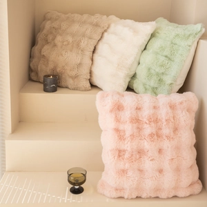 Detailed view of plush faux rabbit fur pillows with embossed square texture in soft tones
