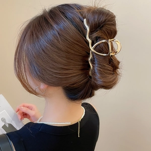 Detail view of the sleek golden wavy hair claw clip styled in a modern French twist