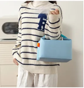 Blue insulated lunch bag with orange accents shown in a modern kitchen setting