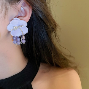 Detail shot of lilac fabric flower earrings with matching purple beads worn by a model