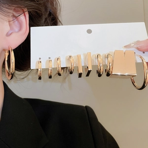 Detail showing a set of gold geometric C-shaped hoop earrings on white card with model display