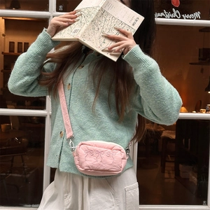 Detail of pink embroidered bow crossbody bag with lightweight fabric and silver hooks