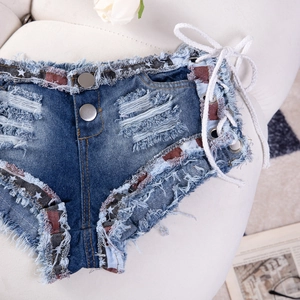 Dettaglio di pantaloncini di denim a vita bassa con toppe a stella e lacci laterali bianchi