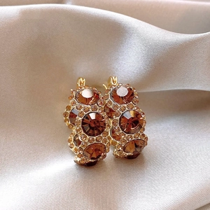 Close-up of champagne gold crystal hoop earrings with brown zircons on silk background
