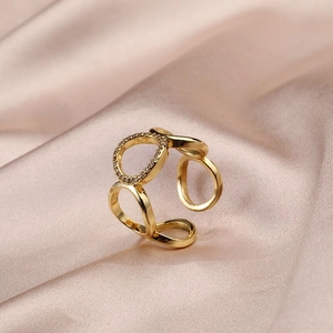Close-up of gold hollow geometric ring with zircon inlay on luxury silk fabric