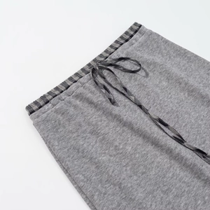 Detailed view of grey sweatpants featuring a black plaid elastic waistband and drawstring