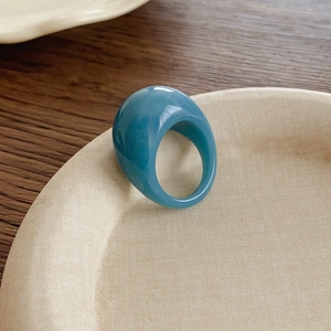 Gros plan d'une bague ovale en résine bleu Morandi sur une assiette en céramique lisse