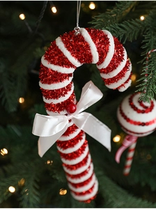 Detail of red and white glitter candy cane ornament with bow on a Christmas tree
