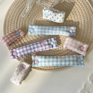 Macro detail of fabric cable organizers in plaid patterns with button fasteners on a mat