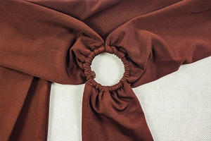 Détail de l'anneau métallique et du tissu froncé rouge-brun sur la combinaison