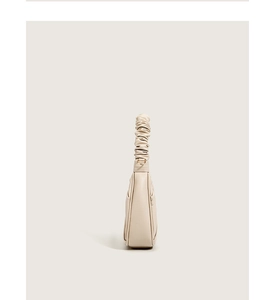 Side view of beige cloud bag featuring a unique pleated handle and smooth texture
