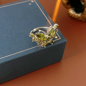 Gros plan sur la bague papillon vert olive avec zircons sur une boîte à bijoux bleue