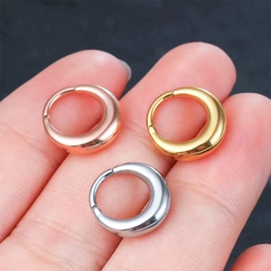 Three-color G23 titanium seamless nose rings and ear hoops shown on finger for scale