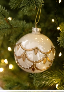 Detail of 8cm cream white matte Christmas ball with golden glitter patterns on green tree